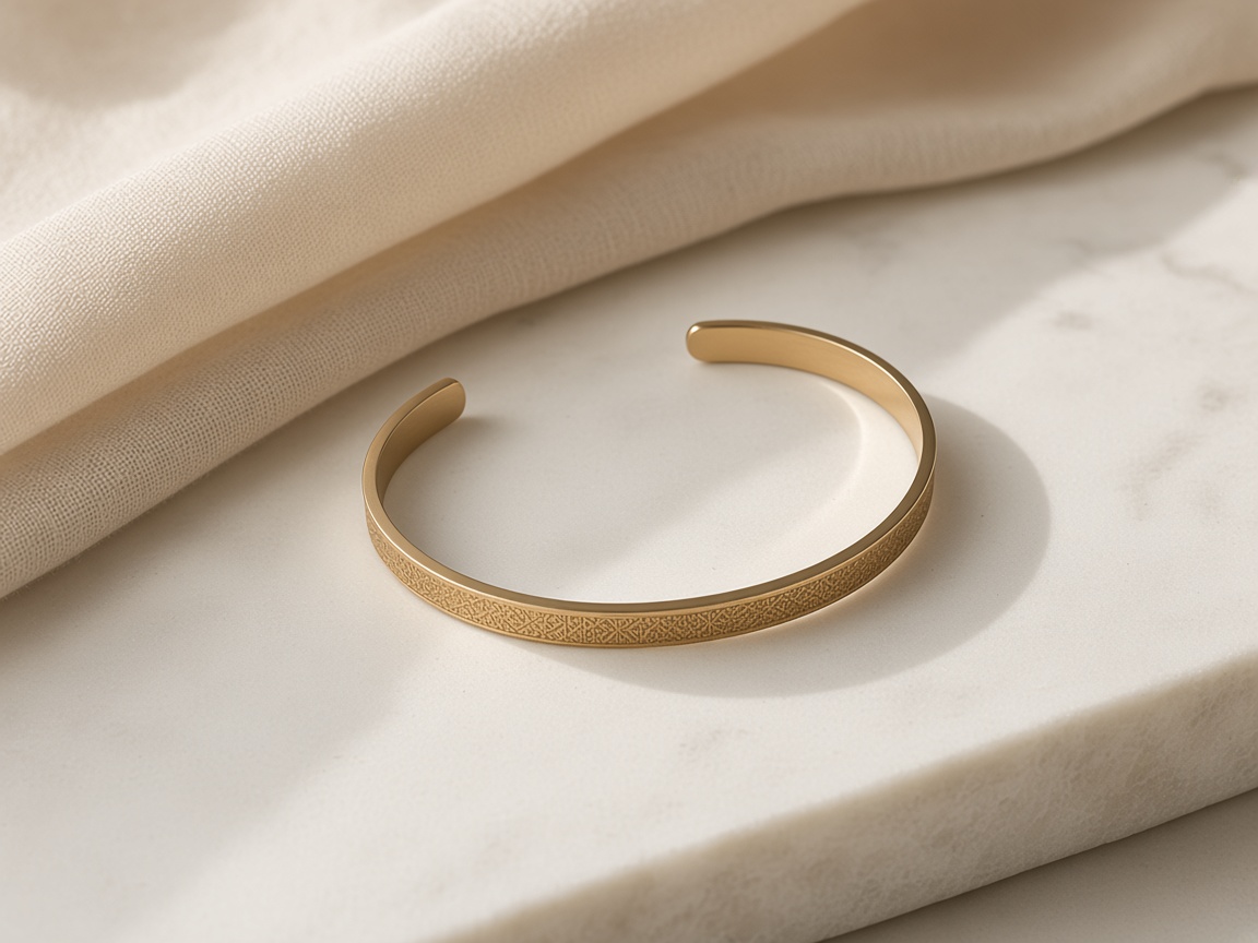 Gold engraved open cuff bracelet on cream linen and marble